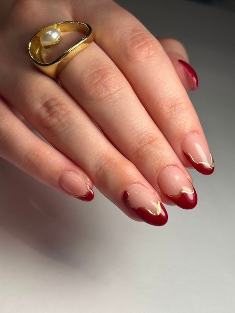 Uñas almendradas con francesa roja y línea dorada