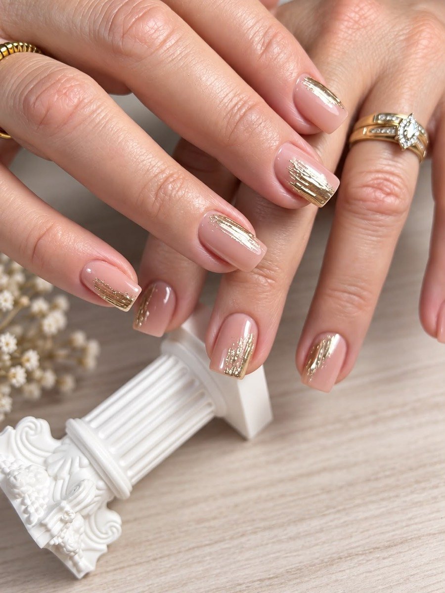 Uñas cuadradas cortas en nude con pinceladas de lámina dorada en las puntas